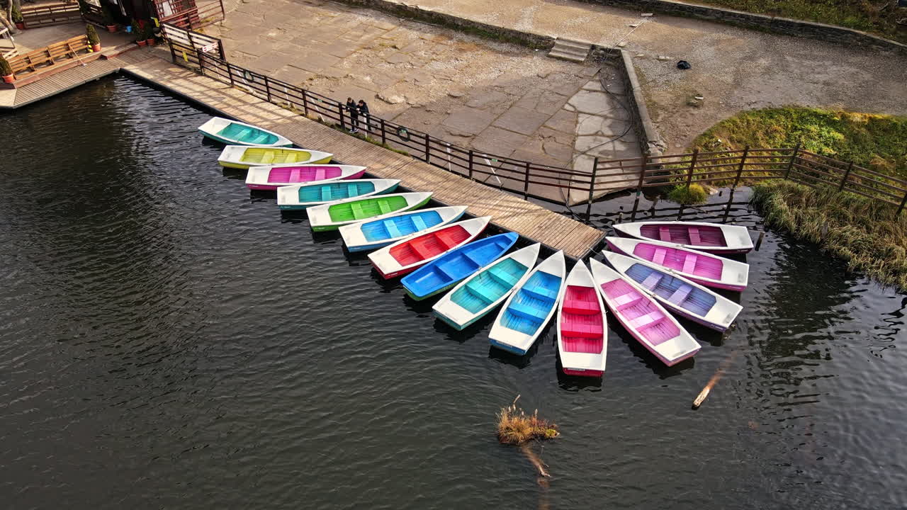 View of The Red Lake with few colored moored boats at a pier, Romania