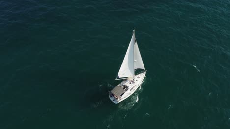 Eine-Luxuriöse-Weiße-Segelyacht-Mit-Wehenden-Segeln-Wird-Nach-Vorne-Geblasen,-Während-Sie-Auf-Den-Kleinen-Wellen-Im-Klaren-Blauen-Mittelmeer-Vor-Der-Küste-Von-Herzeliya-In-Israel-Schaukelt