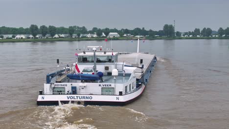 the cargo ship volturno navigating an inland waterway on a cloudy day