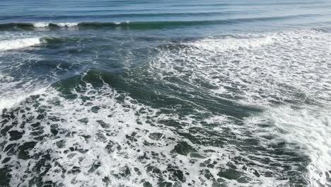 aerial - camera rotates around lone surfer in deep blue water