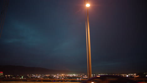 vehicles pass by tracking camera with city lights in background - night