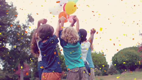 holding balloons with confetti falling, children celebrating in park background