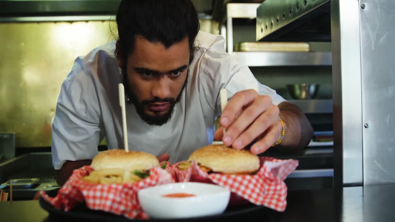 chef feliz colocando brochetas en la hamburguesa en la cocina