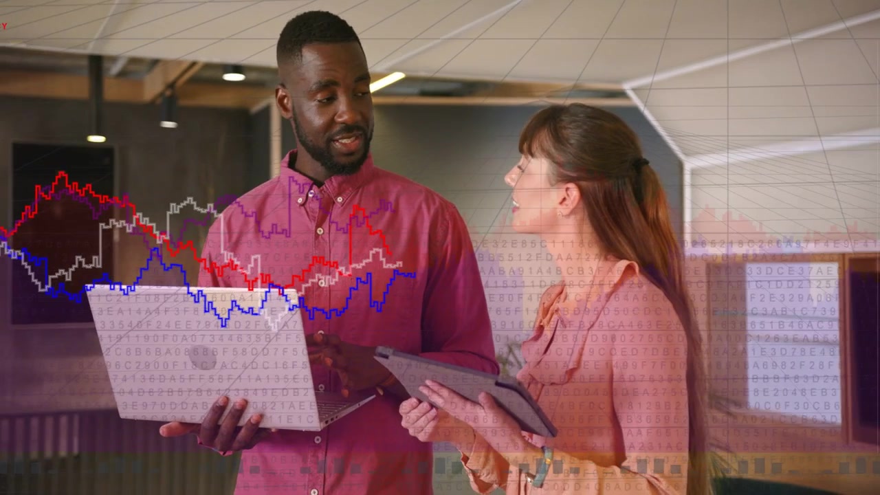 Mann trykker på bærbar PC mens kvinne peker på nettbrett, og analyserer forretningsdiagrammer som ligger over skjermene.