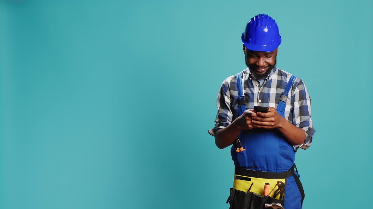 Construction worker texting messages on smartphone