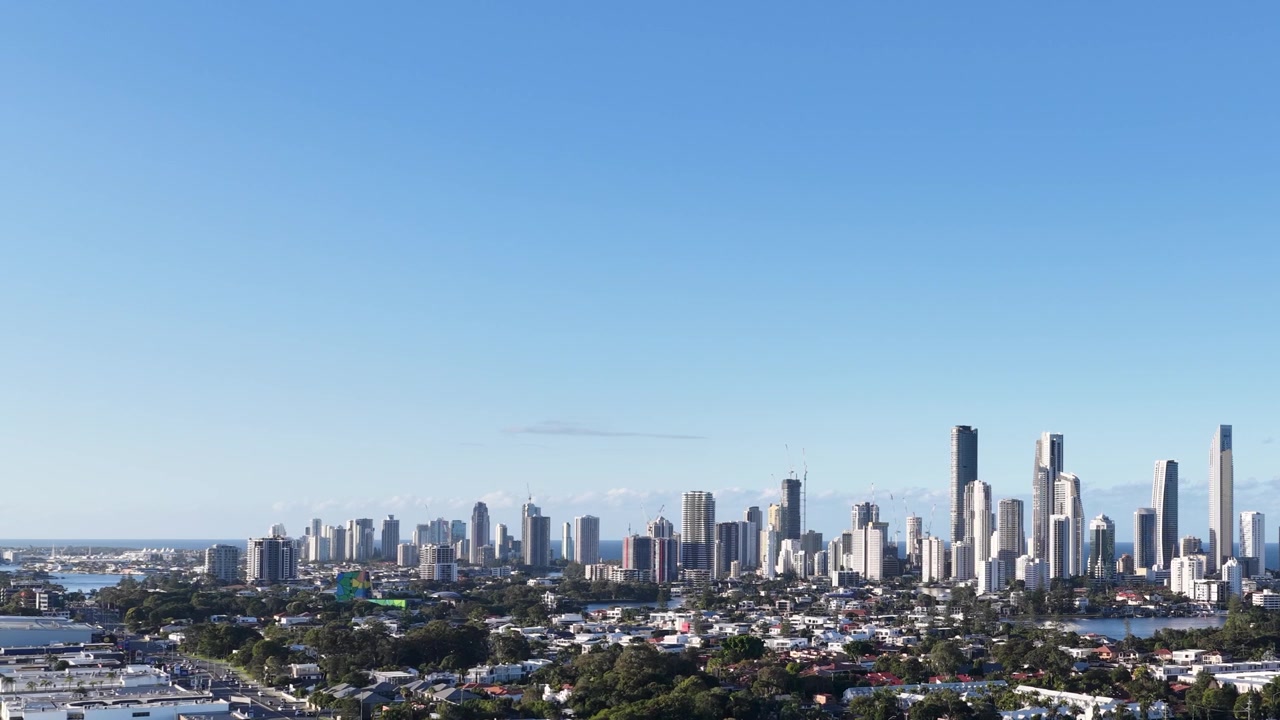 Static wide shot of a modern coastal city skyline under a clear blue sky.