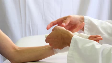 Physiotherapist-putting-bandage-on-injured-hand-of-patient