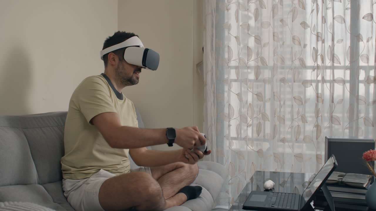 Man navigates VR menu and plays intense game with controller while sitting on couch