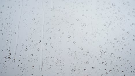 una vista de primer plano en cámara lenta de las fuertes gotas de lluvia se ve a través de un vidrio de la ventana