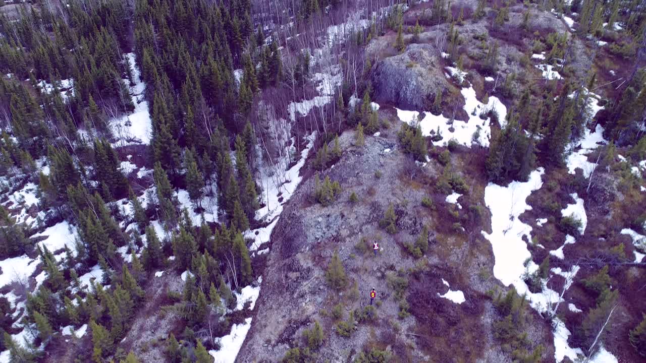 mostrar a los hombres caminar sobre un gran acantilado rodeado de bosque nórdico