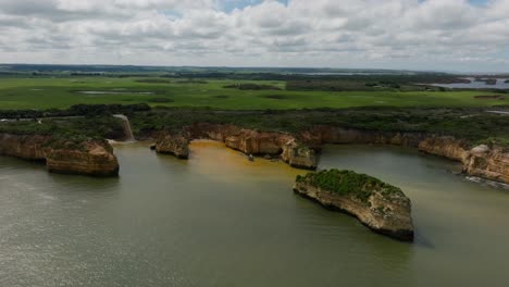 video de avión no tripulado desde la gran carretera del océano en victoria en un día nublado, mostrando la costa de color naranja con la vegetación en el fondo