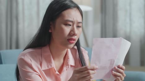 close up of asian woman looking at the bill and having a headache due to financial problem