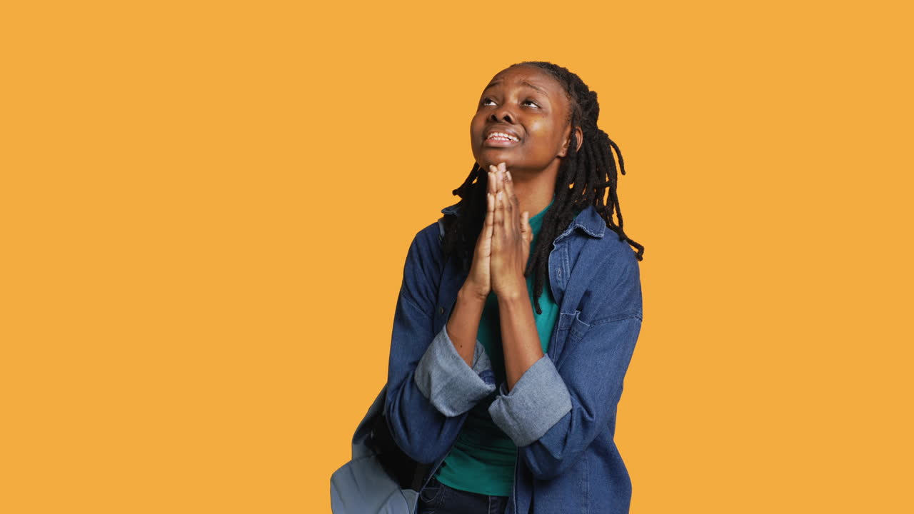 Religious girl doing worship gesturing, waiting for miracle, studio background