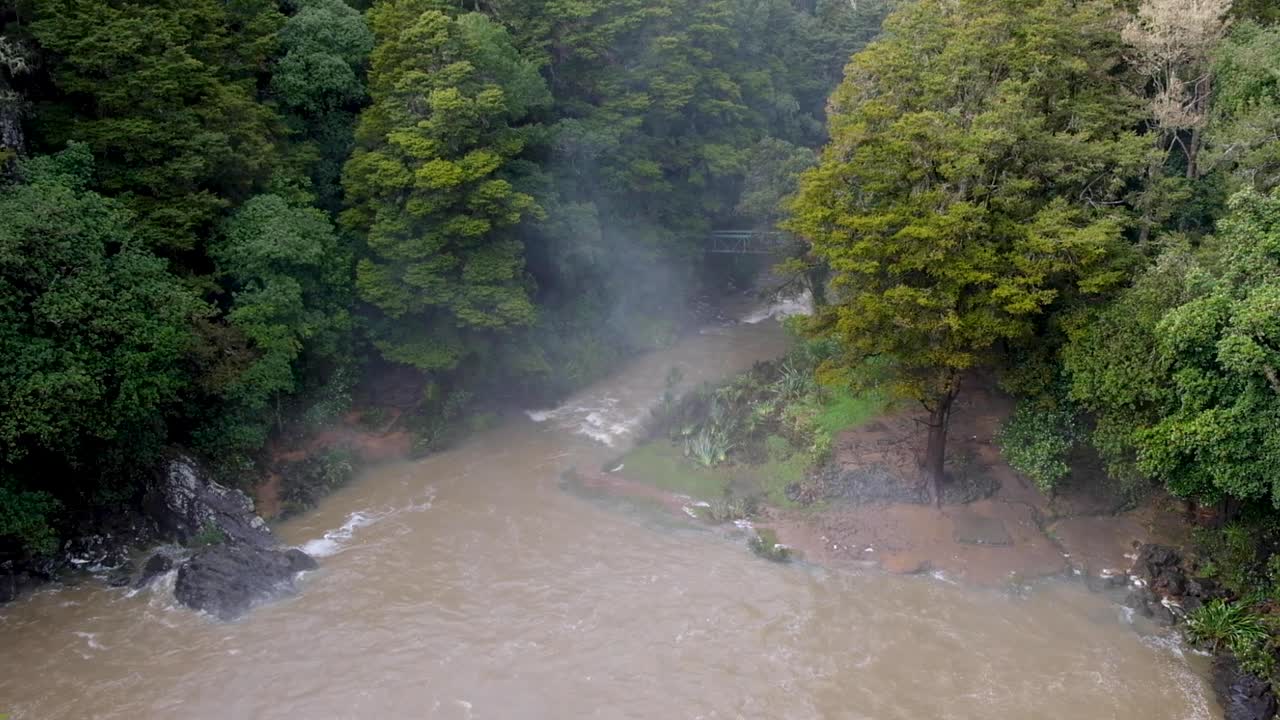 뉴질랜드 북부 오테아로아 (aotearoa) 의 나무 숲 위에 흐릿한 스프레이와 함께 홍수 중에 오투이하우 가레이 폭포의 경치.