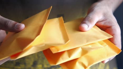 hands holding a stack of yellow envelopes