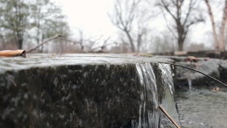 close up slow motion shot of a small waterfall falling over a rock ledge