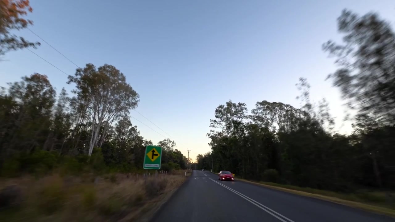 Rozmycie ruchu uchwyca czerwony samochód pędzący zalesioną drogą w Pillar Valley w Australii