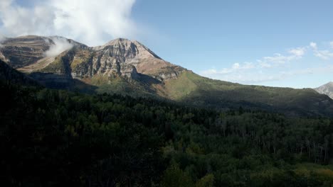 Fliegen-Durch-Einen-Wald-In-Richtung-Eines-Schroffen-Berges,-Während-Das-Morgendliche-Sonnenaufgangslicht-Den-Gipfel-Berührt