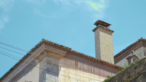 Shooting-the-roof-of-a-house-where-there-are:-a-small-bell-tower,-a-chimney,-wild-plants