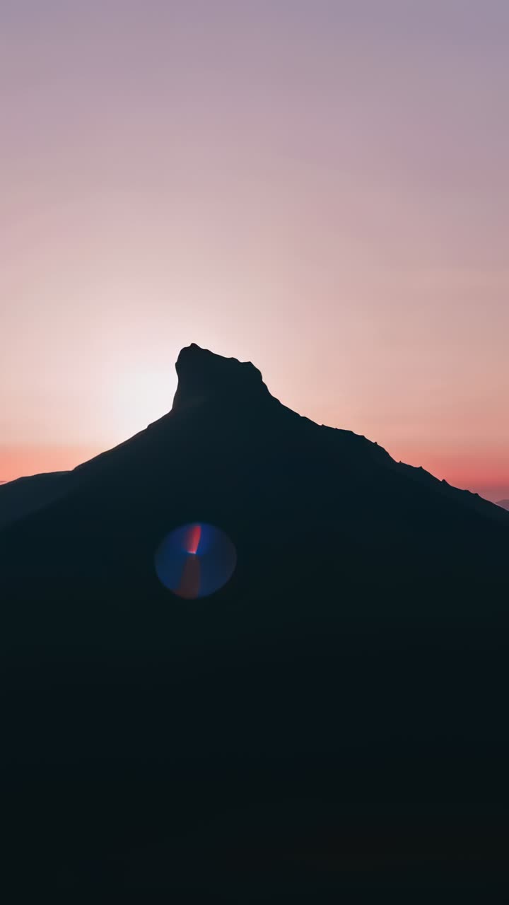 Vertical video: Framing peak with notch while sun peeking through at sunrise, starburst lens flare