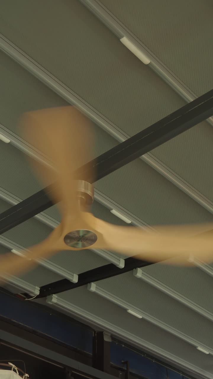 Ceiling Fan with Wooden Blades Spinning Under a Modern Roof