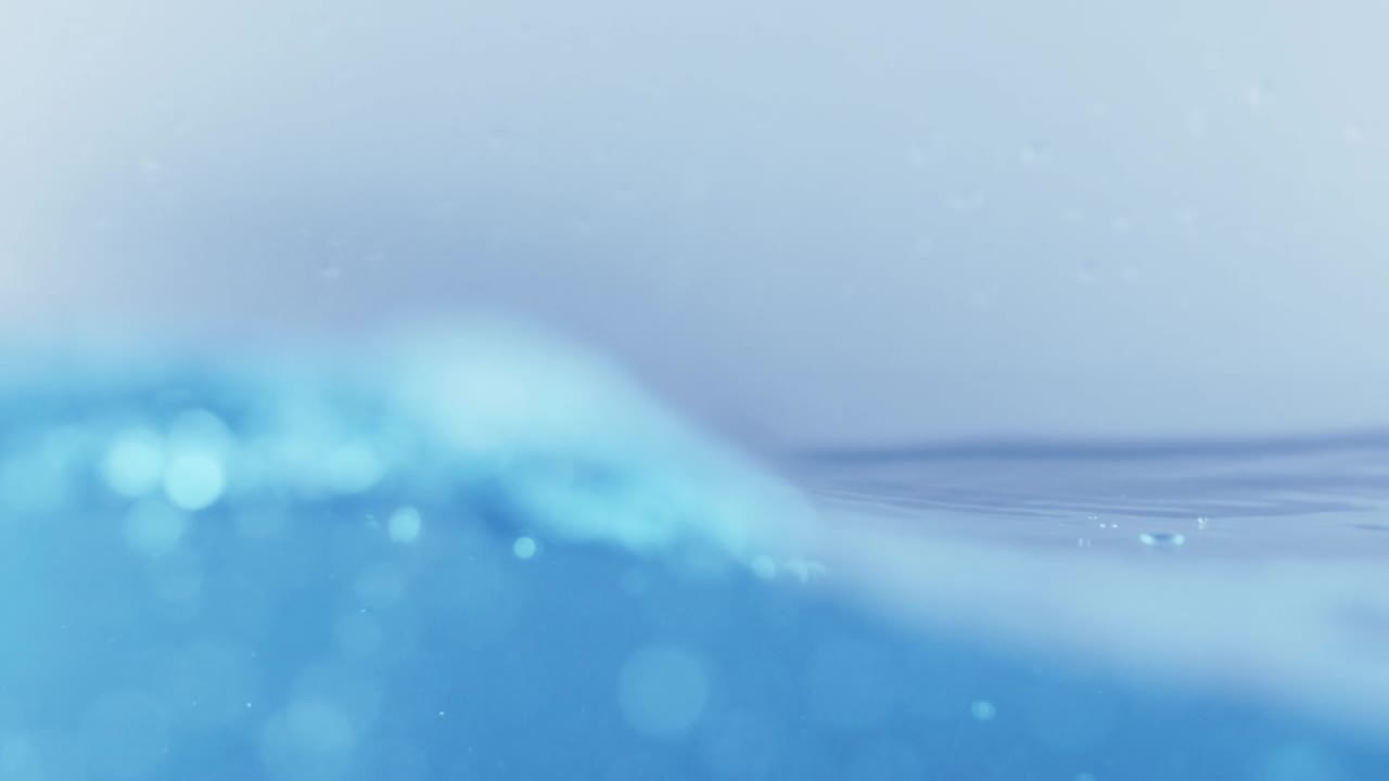 슬로우 모션의 깨끗한 물 표면은 물이 튀는 상점으로 화면을 채우고 기포로 액체 표면을 흔들고 있습니다.