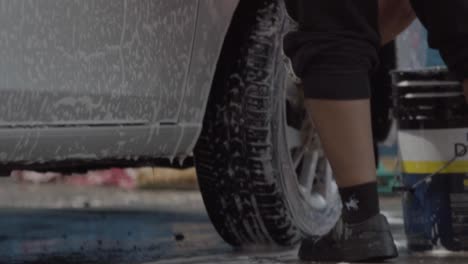 worker cleaning car wheel with soap. slow motion