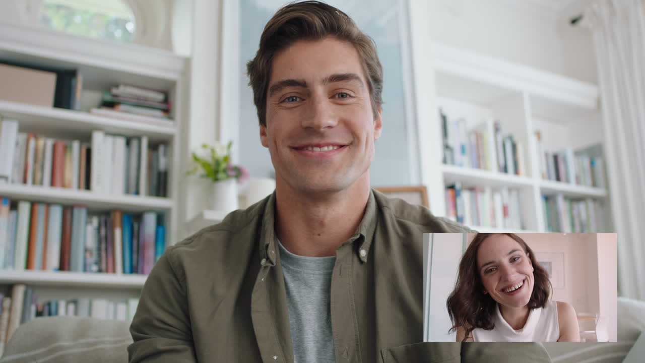 매력적인 남자가 웹캠을 사용하여 여자친구와 비디오 채팅하며 미소 짓고 온라인 장거리 관계를 즐기고 있습니다.