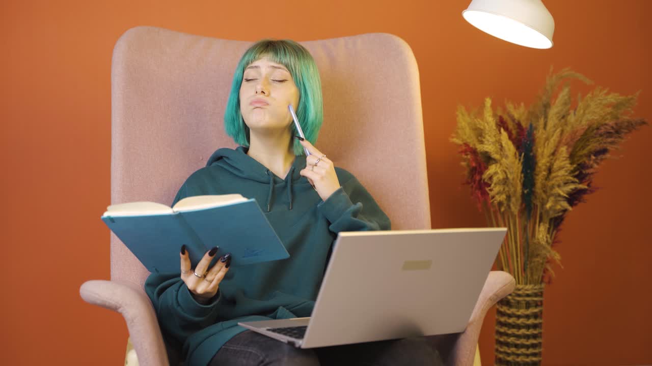 노트북을 들고 있는 젊은 여성이 생각하고 메모를 합니다.