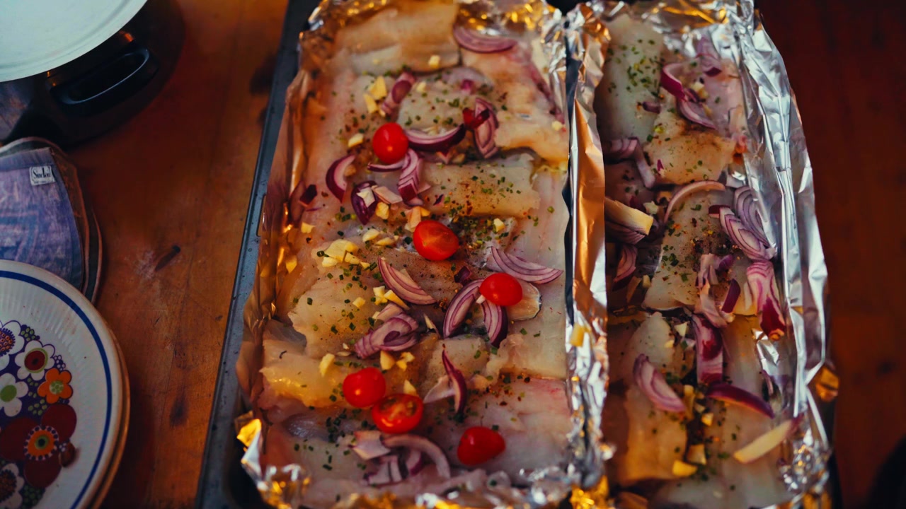 Filetto di pesce arrosto guarnito con cipolle e pomodorini. Ripresa dall'alto