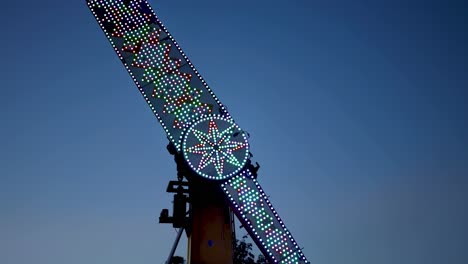 illuminated ride rotating against evening sky