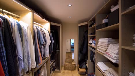 slow establishing shot of men's clothing hanging within a walk-in closet