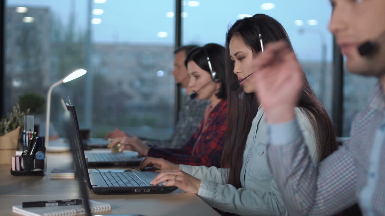Call center agents working at their desks with headsets and laptops