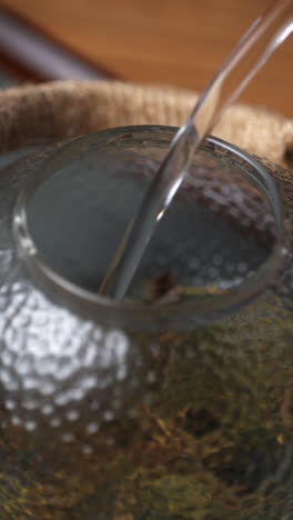 pouring water into a glass teapot