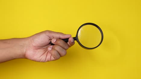 hand holding a magnifying glass on a yellow background