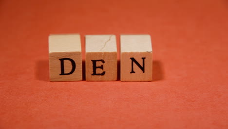 composing the word deny with wooden letters on a red background