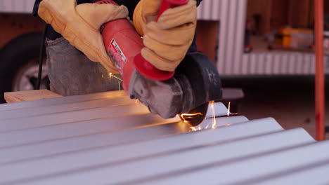 a construction worker using a power tool angle grinder to cut metal and send glowing bright sparks flying in slow motion