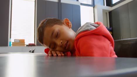 Side-view-of-Asian-schoolboy-sleeping-over-the-desk-in-classroom-at-school-4k