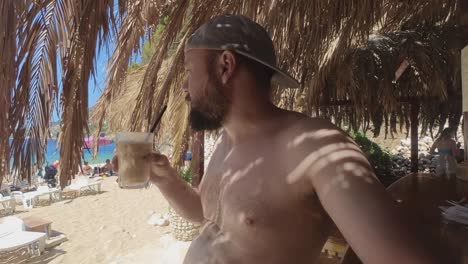 modelo masculino bebiendo café helado en la playa de dubrovnik