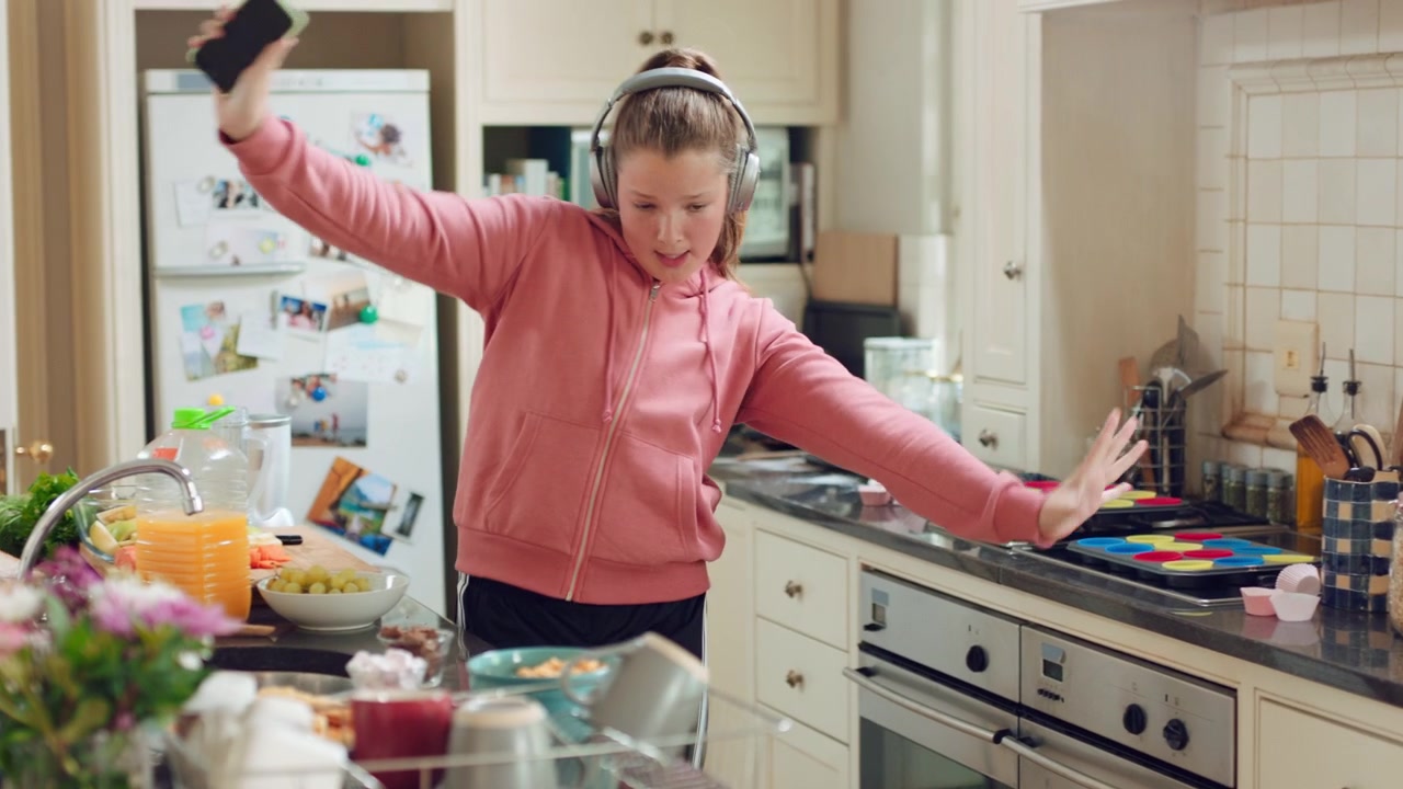 Happy Teenage Girl Dancing and Singing in Kitchen