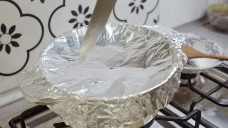 cutting holes inside foil paper cover on top of pot with indian biriyani rice cooking inside it