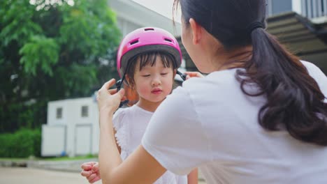 mother putting a helmet on her daughter