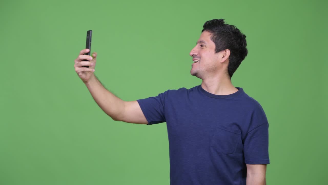 Happy Hispanic man video calling with phone