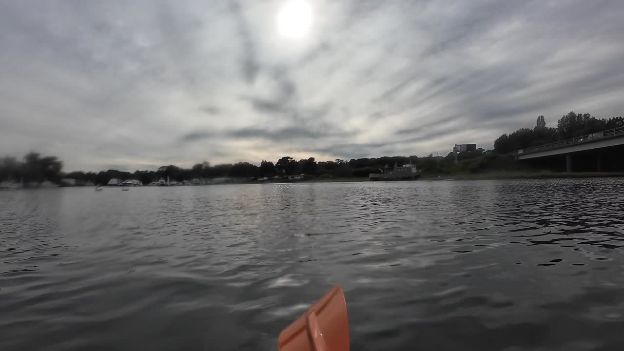 Paddle through the tranquil waters of the River Hamble under an overcast sky in this serene, unpopulated landscape. Experience the calming reflections and gentle ripples