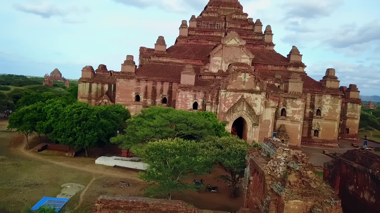 A cinematic crane-style establishing shot highlighting the redbrick temple pagodas in Bagan, Myanmar, offering a majestic view of the ancient temples set in the serene landscape.