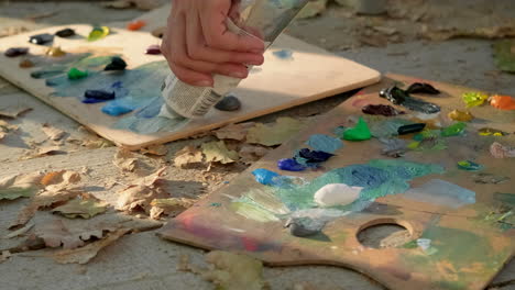 artist painting outdoors with wooden palette