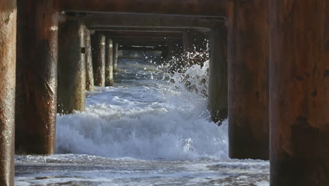 olas que se estrellan bajo un muelle
