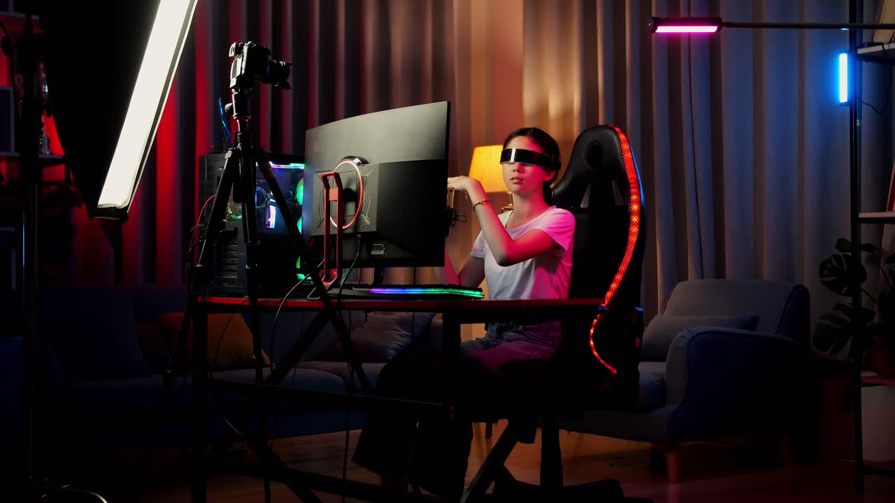 niña asiática que juega juegos, toca y desliza experiencia de realidad virtual en gafas futuristas. jugador tocando el panel de aire. computadora personal en el escritorio iluminada por luz de tira led rgb