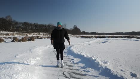 lonely young female is skating outdoor on frozen ice on pond. woman in figure skates is ice skating on frozen lake at sunny freezy day. winter sport activities