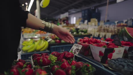 a woman picks strawberries from the local market